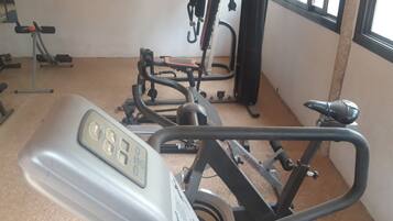 A gym with exercise equipment including a stationary bike, a rowing machine, and weightlifting machines.