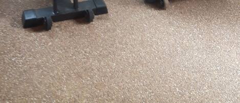 Two stationary bikes in a room with a window and a textured floor.