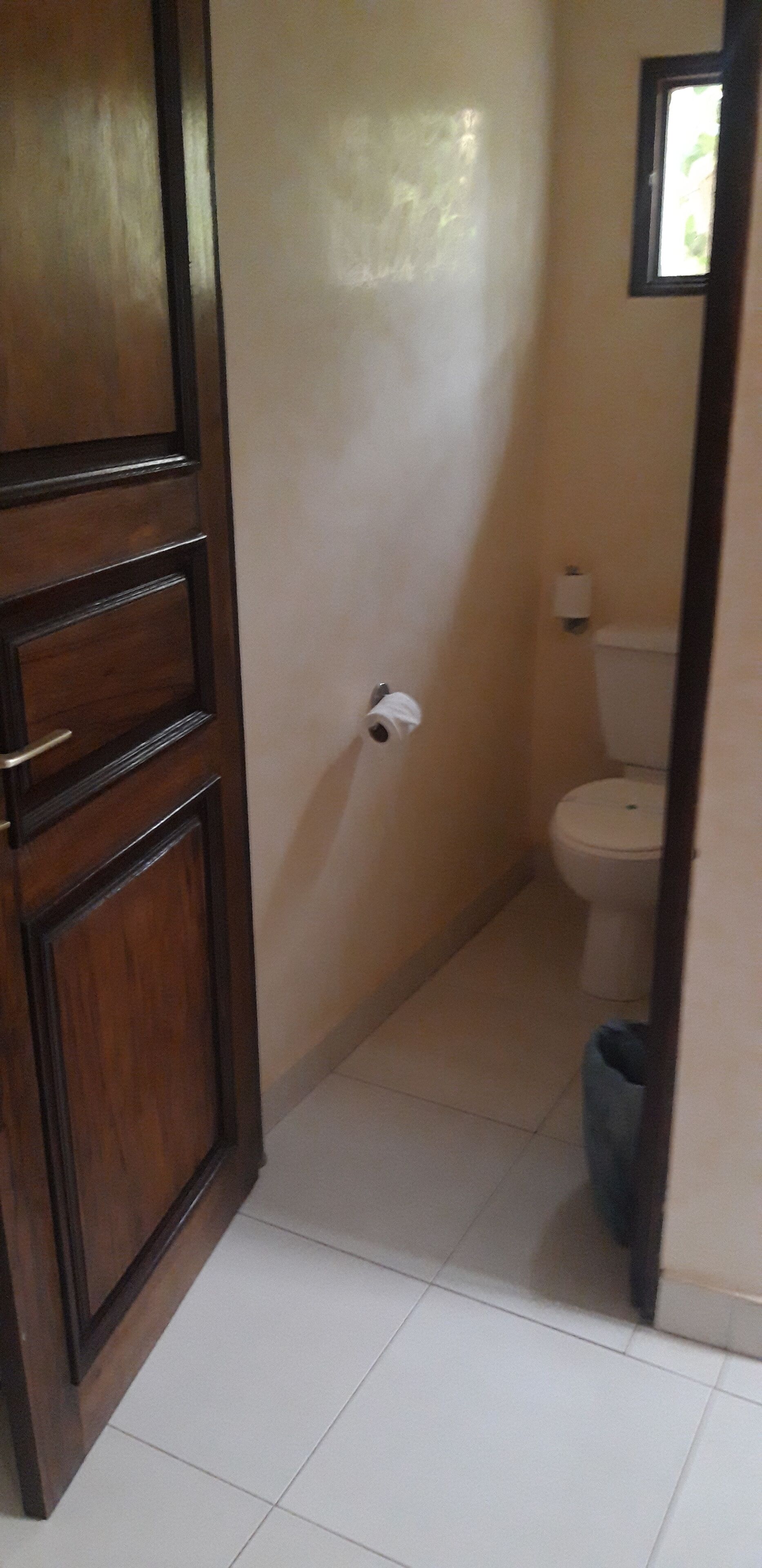 Un baño con inodoro, dispensador de toallas de papel y un cubo de basura.