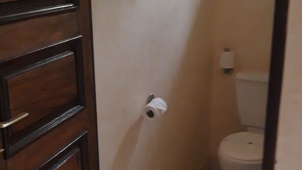Une salle de bain équipée de toilettes, d’un distributeur d’essuie-tout et d’une poubelle.