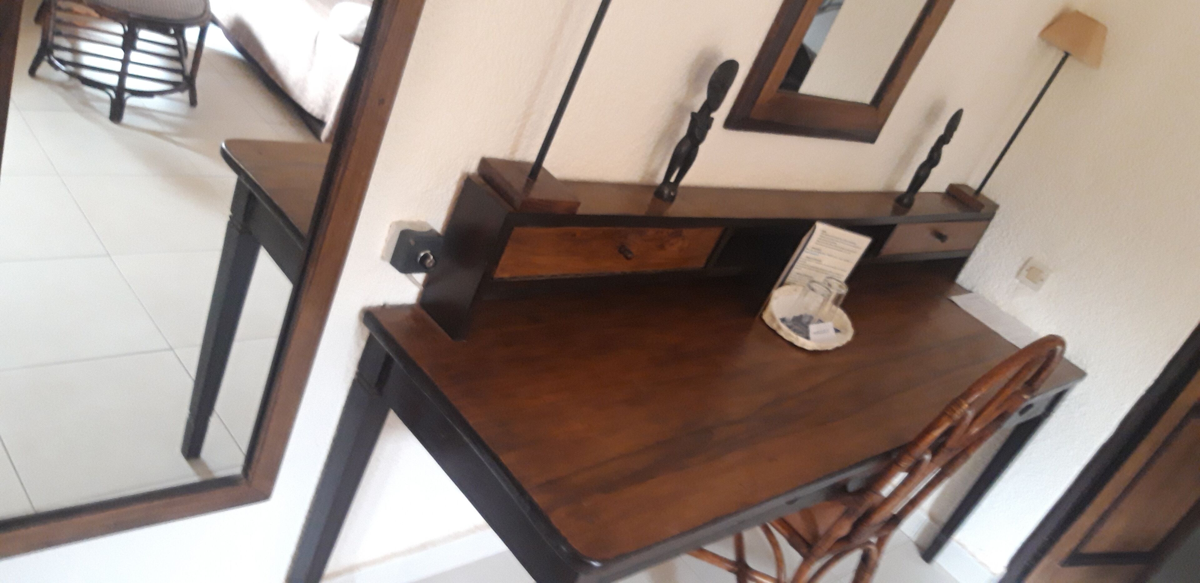 A wooden dining table with chairs, a mirror, and a lamp.
