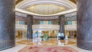 A spacious lobby with a high ceiling, large columns, and a central decorative element. - Lee Wan Hotel (Dalian)