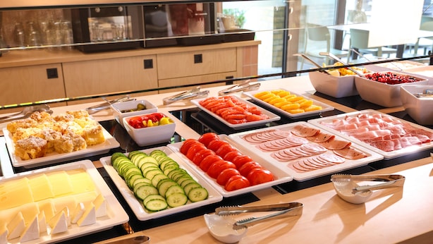 Un buffet proposant une variété de plats, notamment des fruits, des légumes et des viandes.