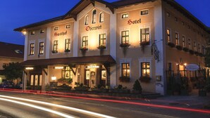 Un hotel europeo tradicional con fachada iluminada, múltiples ventanas y jardineras florales.
