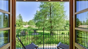 A balcony with a view of a park, a wooden pergola, and two wooden chairs. - Hotel Gasthof Oberwirt (Obing)