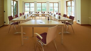 Ein Konferenzraum mit einem langen Tisch, mehreren Stühlen und großen Fenstern.