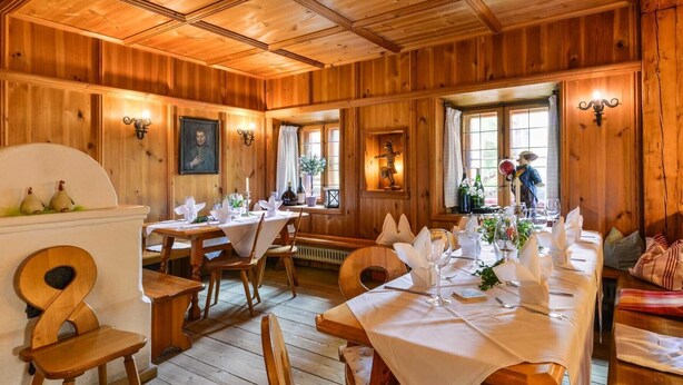 A wooden interior with tables set for dining, wooden walls, and a ceiling with wooden beams. - Hotel Gasthof Oberwirt (Obing)