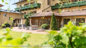 A hotel with a courtyard featuring outdoor seating, a wooden pergola, and a well-maintained lawn. - Hotel Gasthof Oberwirt (Obing)