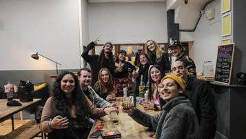 Un grupo de personas sentadas alrededor de una mesa en un comedor informal, con un menú en una pizarra en la pared.