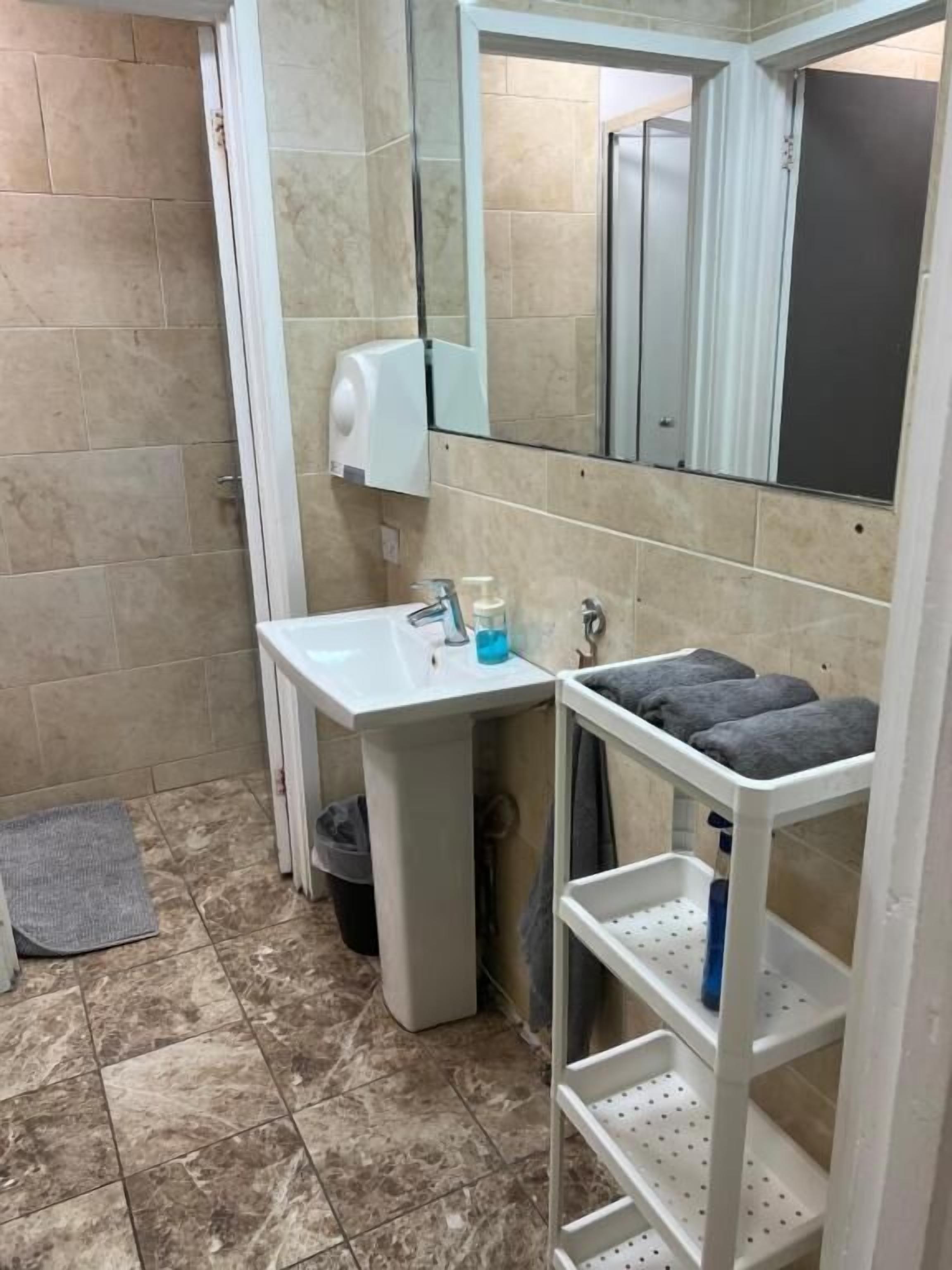 A bathroom with a white sink, mirror, and towel rack.