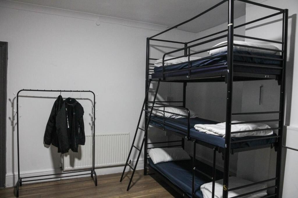 A bunk bed room with a metal ladder and a clothing rack.