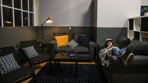 A modern living room with a sofa, two armchairs, a coffee table, and a lamp. - Onefam Waterloo 18-36 years old (London)