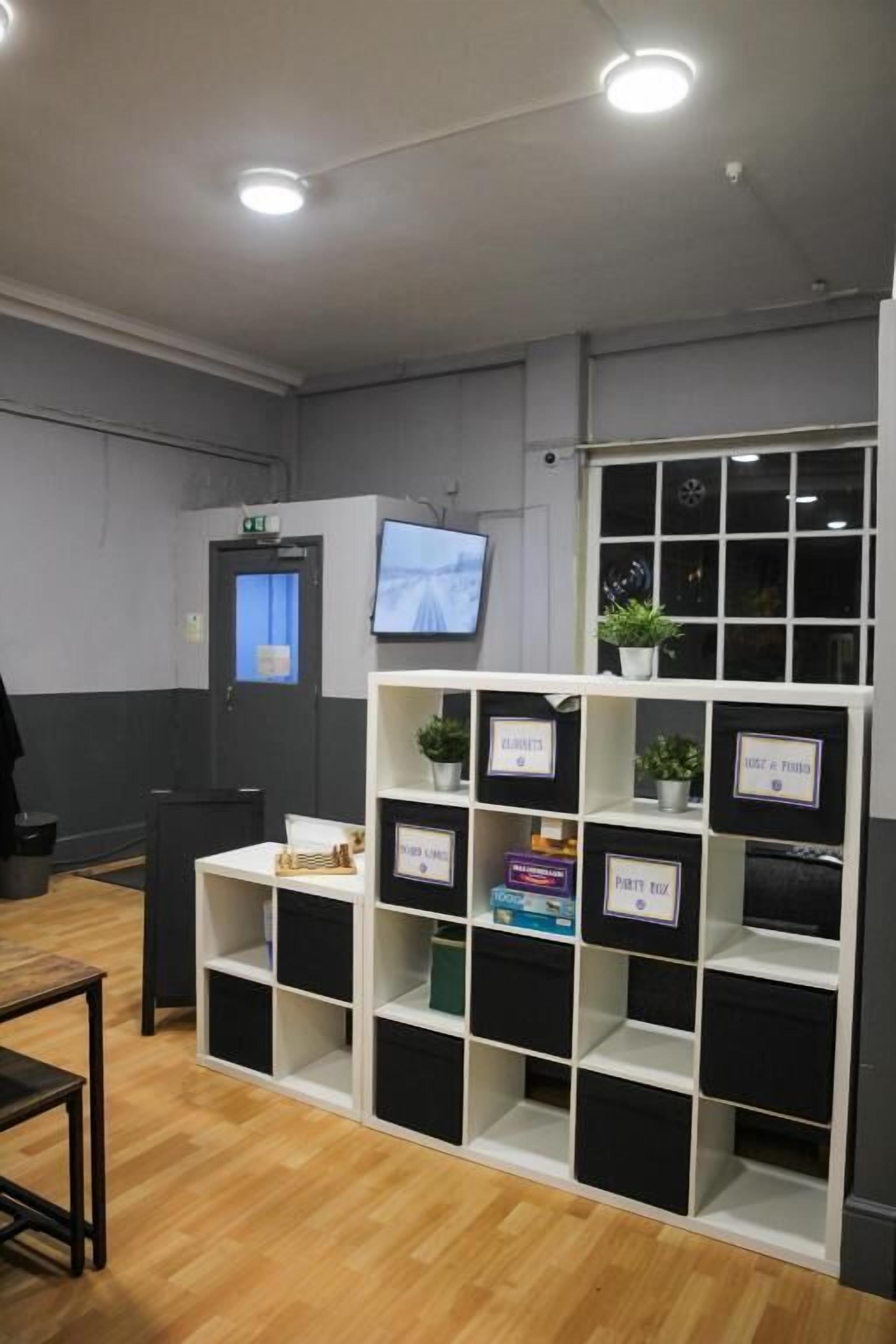 A reception area with a white reception desk, a television mounted on the wall, and a plant on the desk.