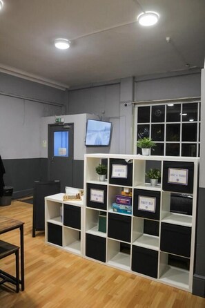 Zona de recepción con un mostrador blanco, un televisor montado en la pared y una planta sobre el mostrador.