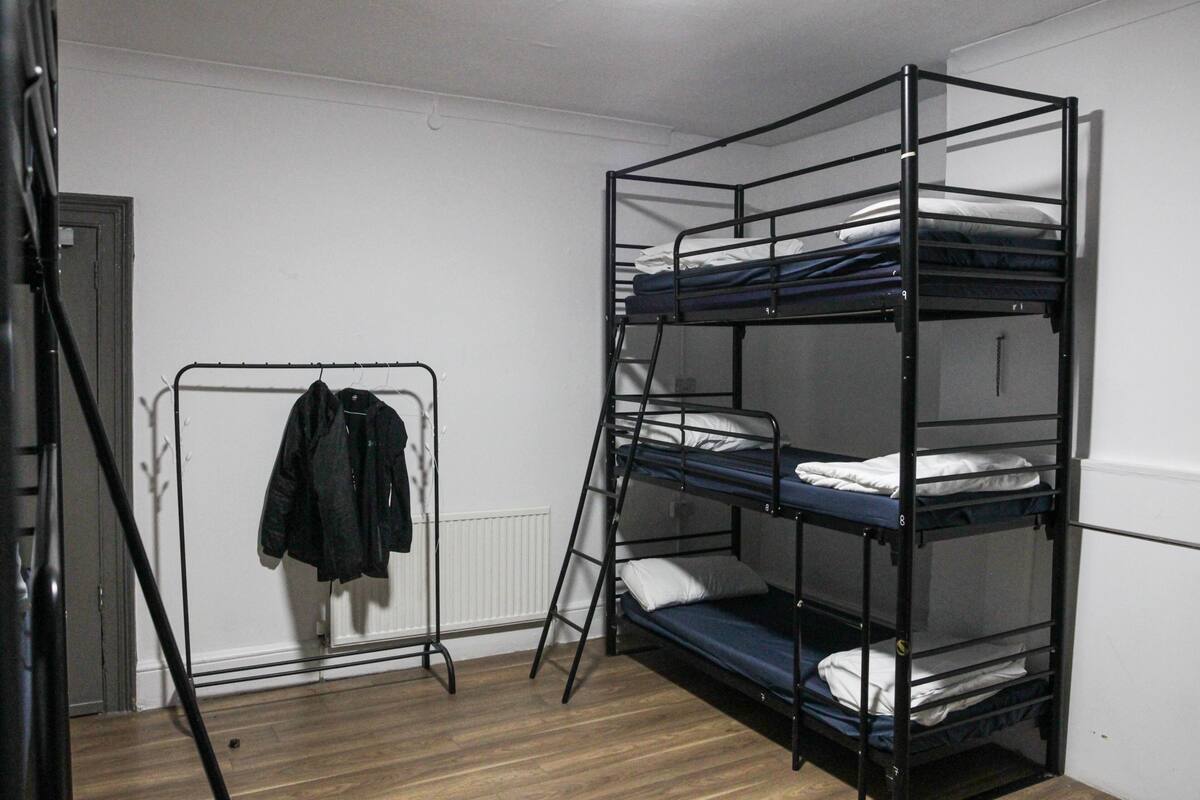 A bunk bed room with a radiator, a coat rack, and a door.