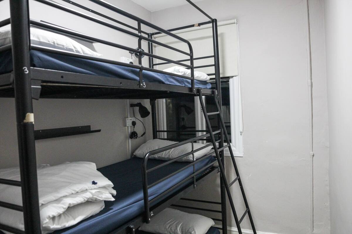 A bunk bed room with a window, a desk, and a chair.