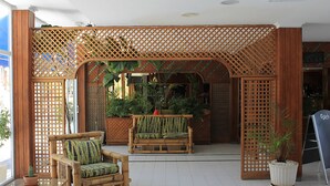 A wooden partition with lattice design, a bamboo sofa with a green cushion, and a potted plant. - Apartamentos Plaza Azul (Tías)