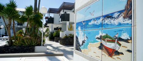 A tiled mural of a beach scene with a boat and seagulls.