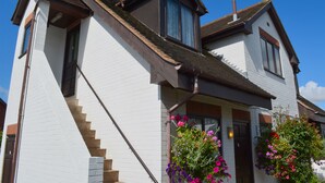 A two-story house with a steeply pitched roof, a visible chimney, and a front entrance with a door and window. - The Bull's Head Inn at Chelmarsh (Bridgnorth)