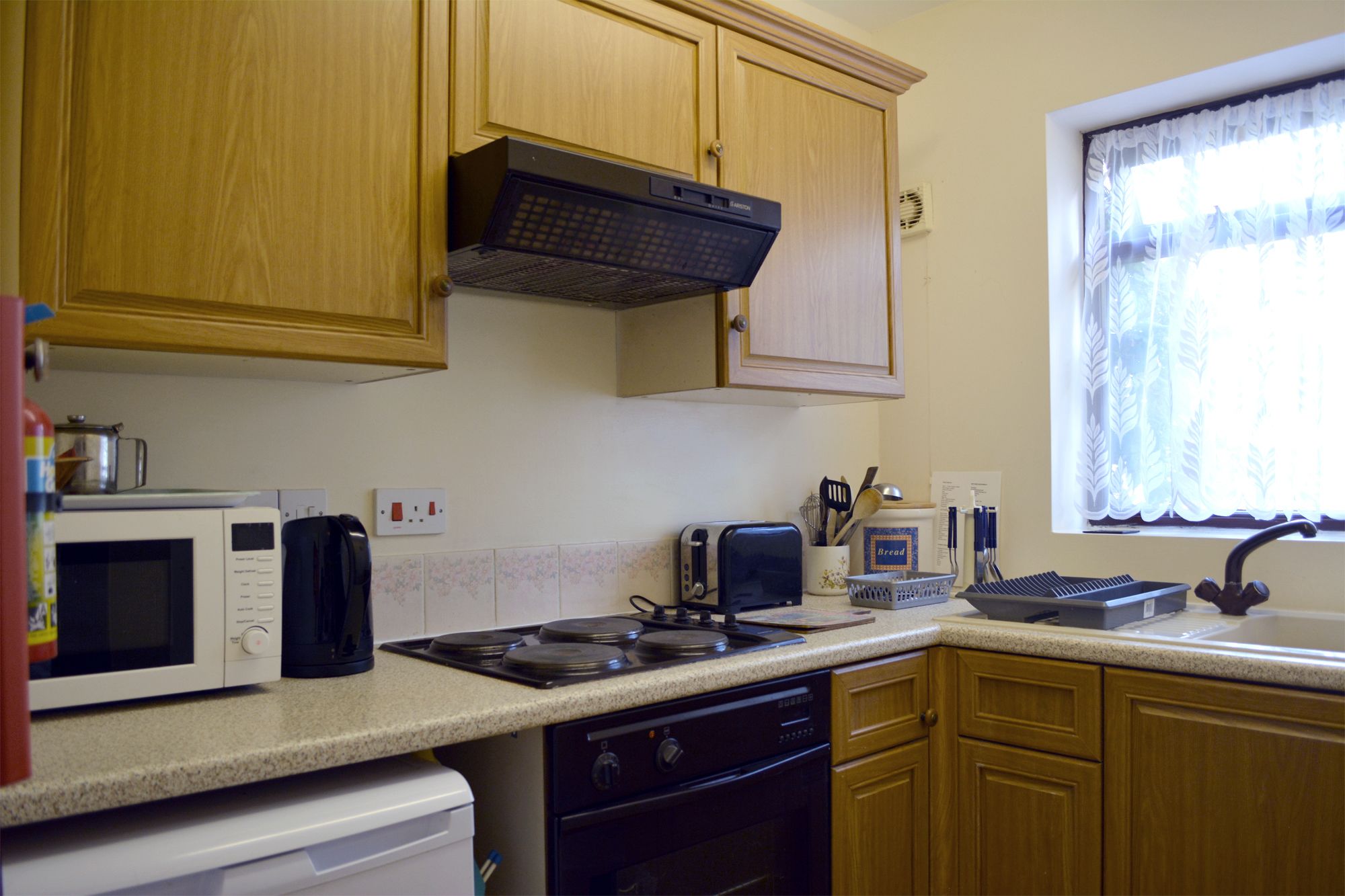 A kitchen with wooden cabinets, a microwave, a toaster, a stove, and a sink.