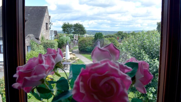 A view through a window of a garden with a pathway, a gazebo, and a building in the background. - The Bull's Head Inn at Chelmarsh (Bridgnorth)