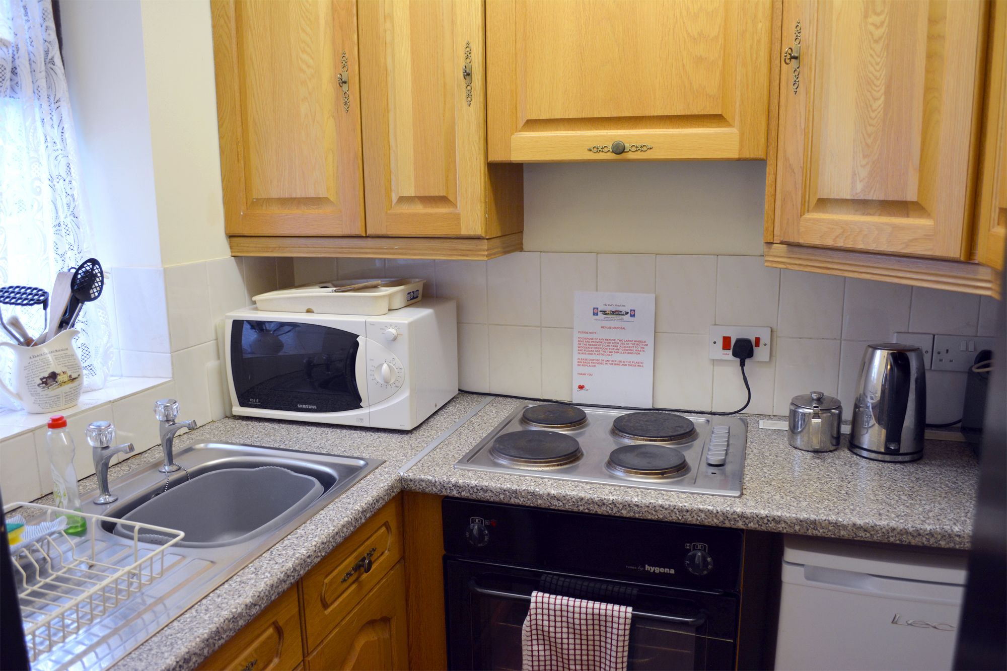 A kitchen with wooden cabinets, a microwave, a stove, a sink, and a dishwasher.