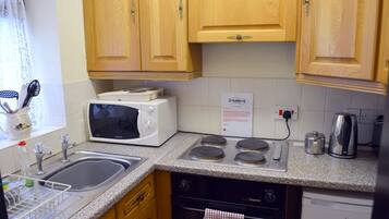 A kitchen with wooden cabinets, a microwave, a stove, a sink, and a dishwasher.