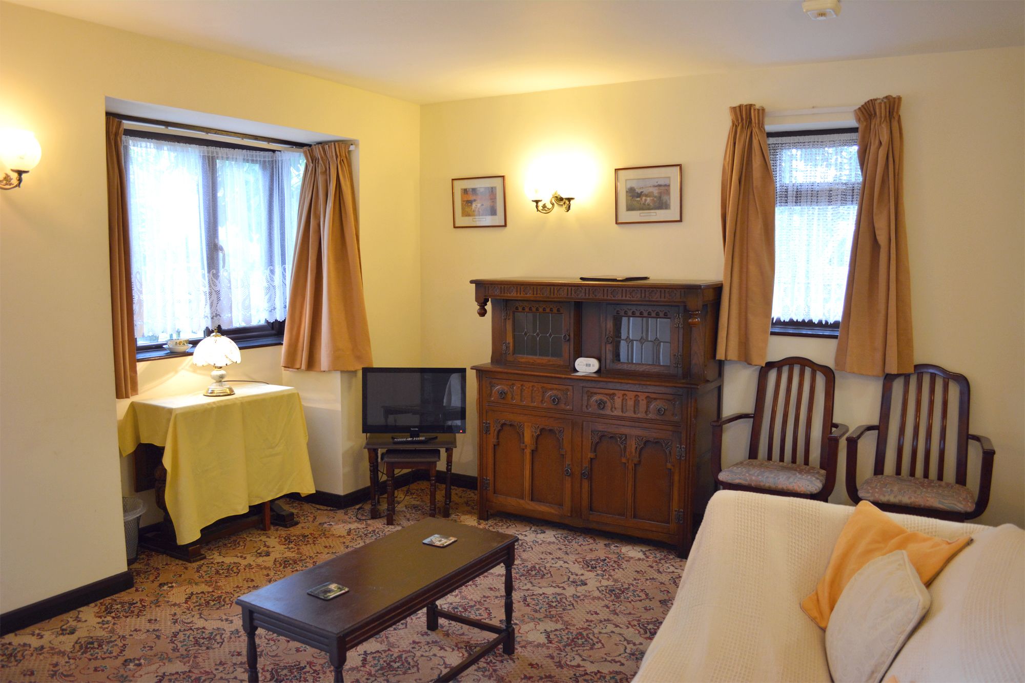 A living room with a sofa, a table with a lamp, a TV, and a cabinet.