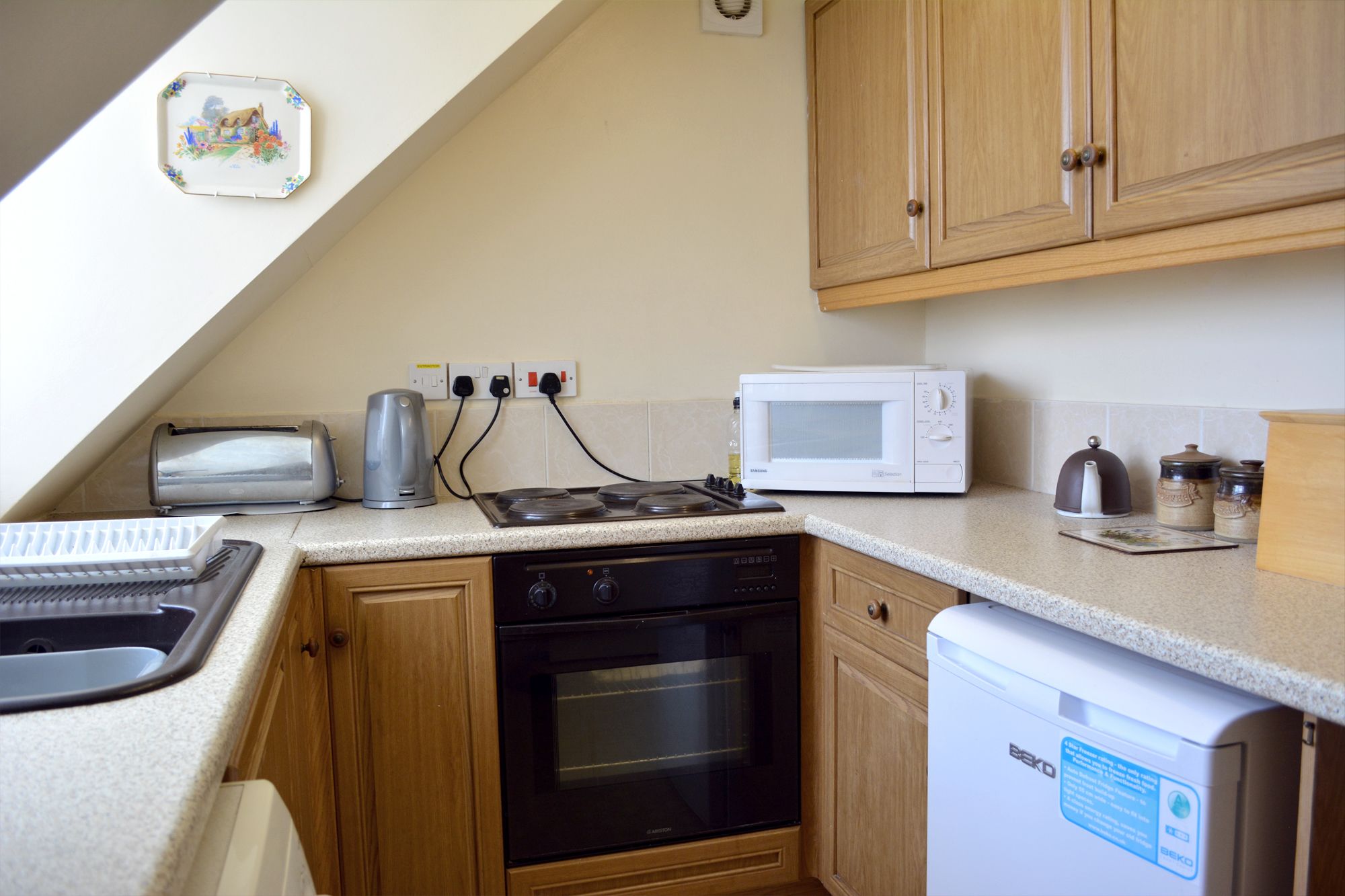 Una cocina compacta equipada con microondas, tostadora, hervidor y horno.