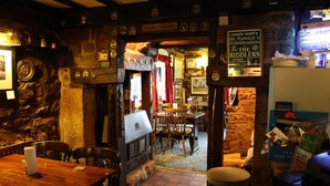 A cozy pub interior with stone walls, wooden furniture, and a sign for Ronnie Scott's St. Patrick's Celebration. - The Bull's Head Inn at Chelmarsh (Bridgnorth)
