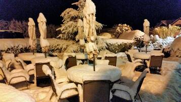 A snow-covered outdoor seating area with tables and chairs.