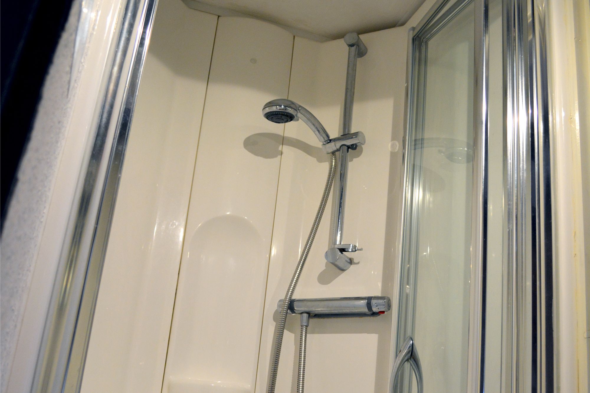 A shower with a handheld showerhead and a handheld faucet.