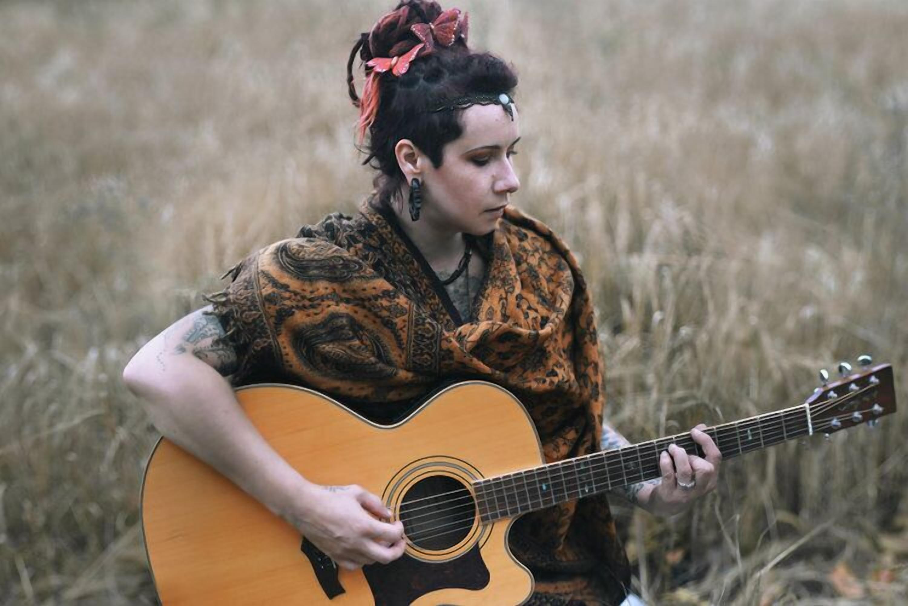 A person playing an acoustic guitar in a natural setting.