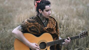 A person playing an acoustic guitar in a natural setting.