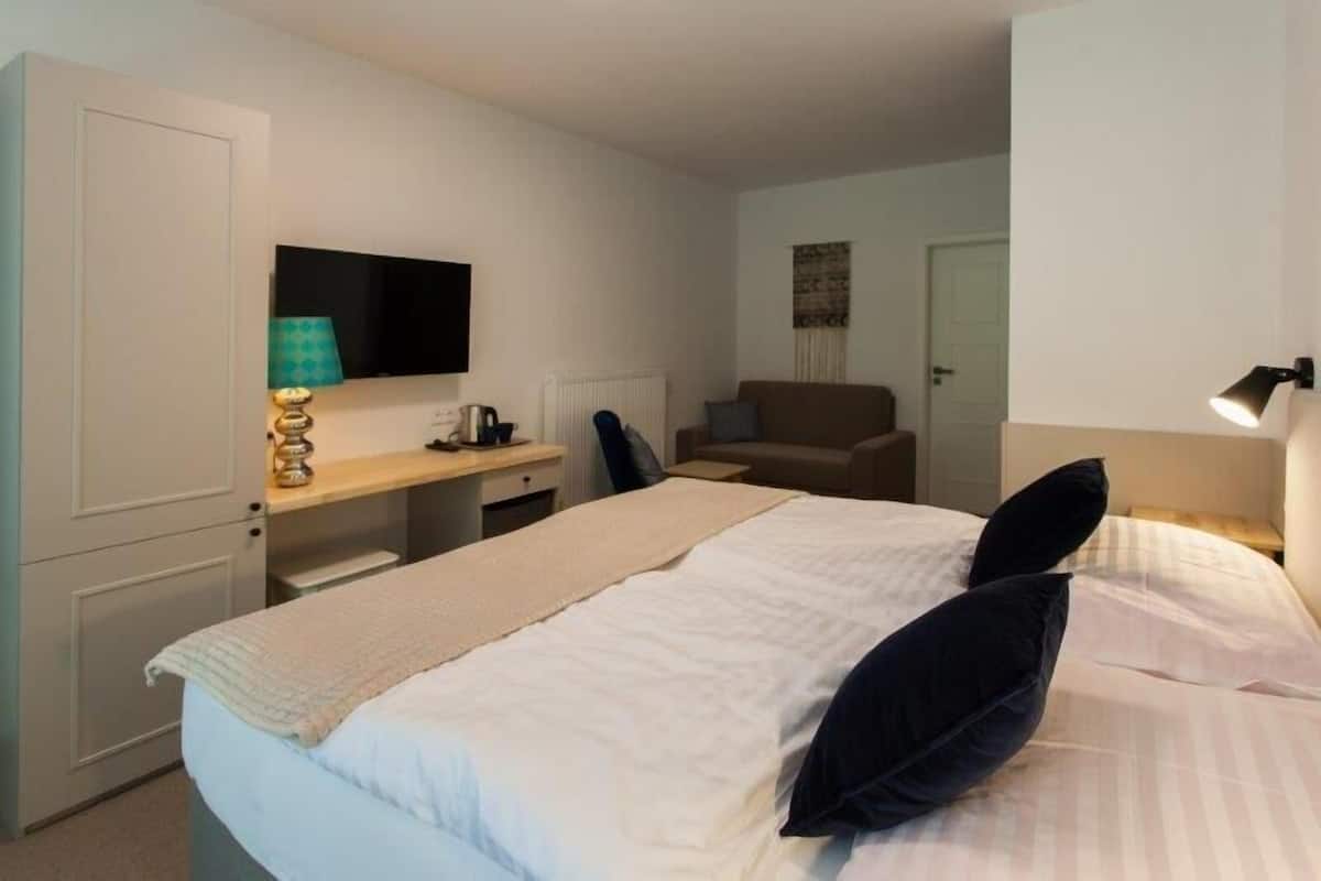 Un dormitorio con cama, escritorio, silla, televisor y lámpara.