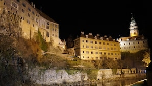 A historic building with a prominent tower, situated beside a river. - Resort-Restaurant Štilec (Kamenný Újezd)