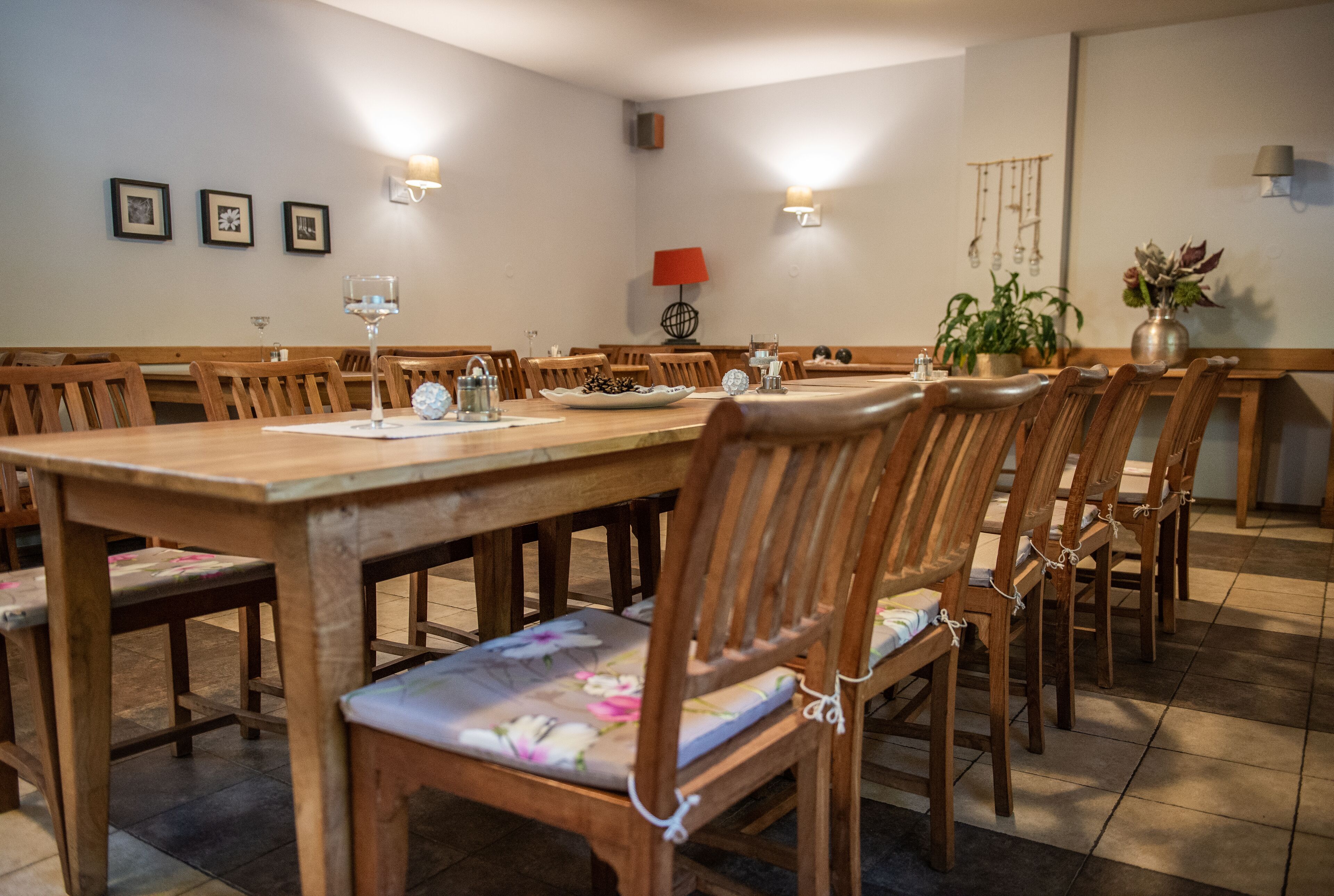 Un comedor con una larga mesa de madera, varias sillas de madera y algunas lámparas fijadas a la pared.