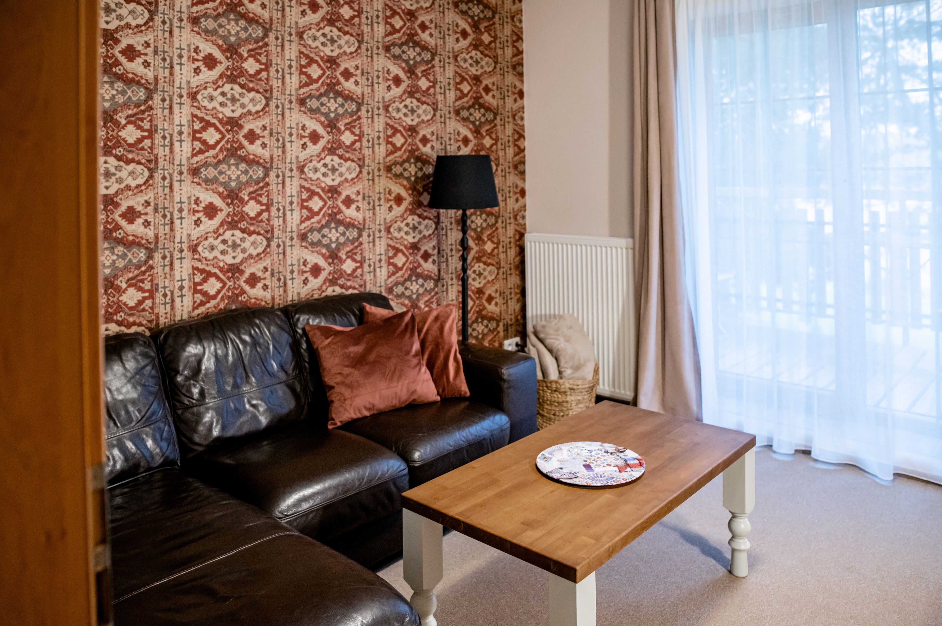Ein Wohnzimmer mit braunem Ledersofa, einem Holztisch und einer raumhaften Wandgestaltung.