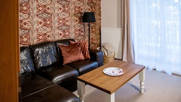 Ein Wohnzimmer mit braunem Ledersofa, einem Holztisch und einer raumhaften Wandgestaltung.