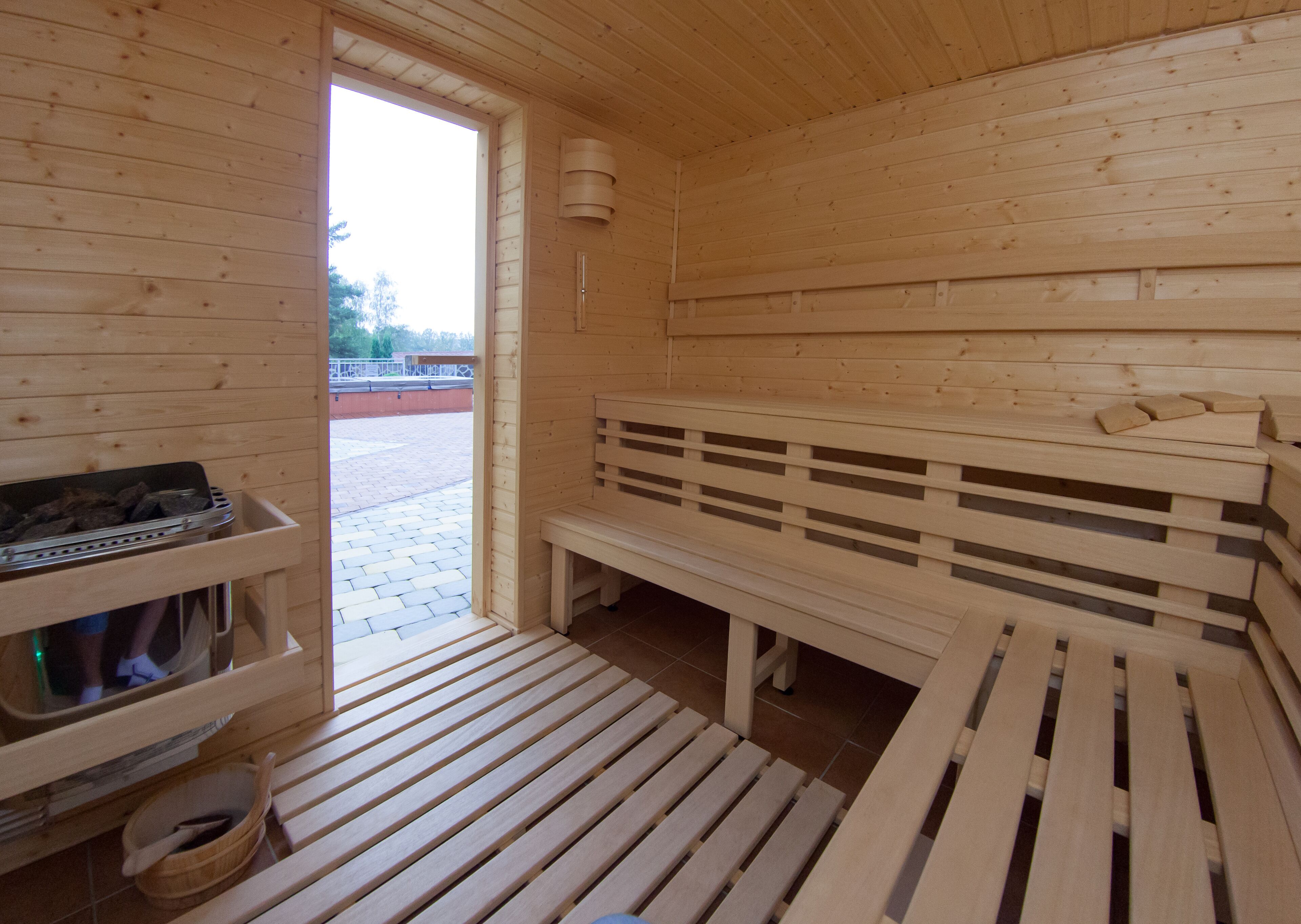 Una sauna de madera con bancos y un asiento, un asiento con una toalla, y un banco con una toalla.
