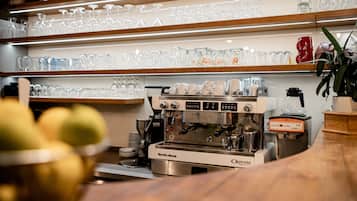 A coffee machine, glassware, and a bowl of fruit on a counter.