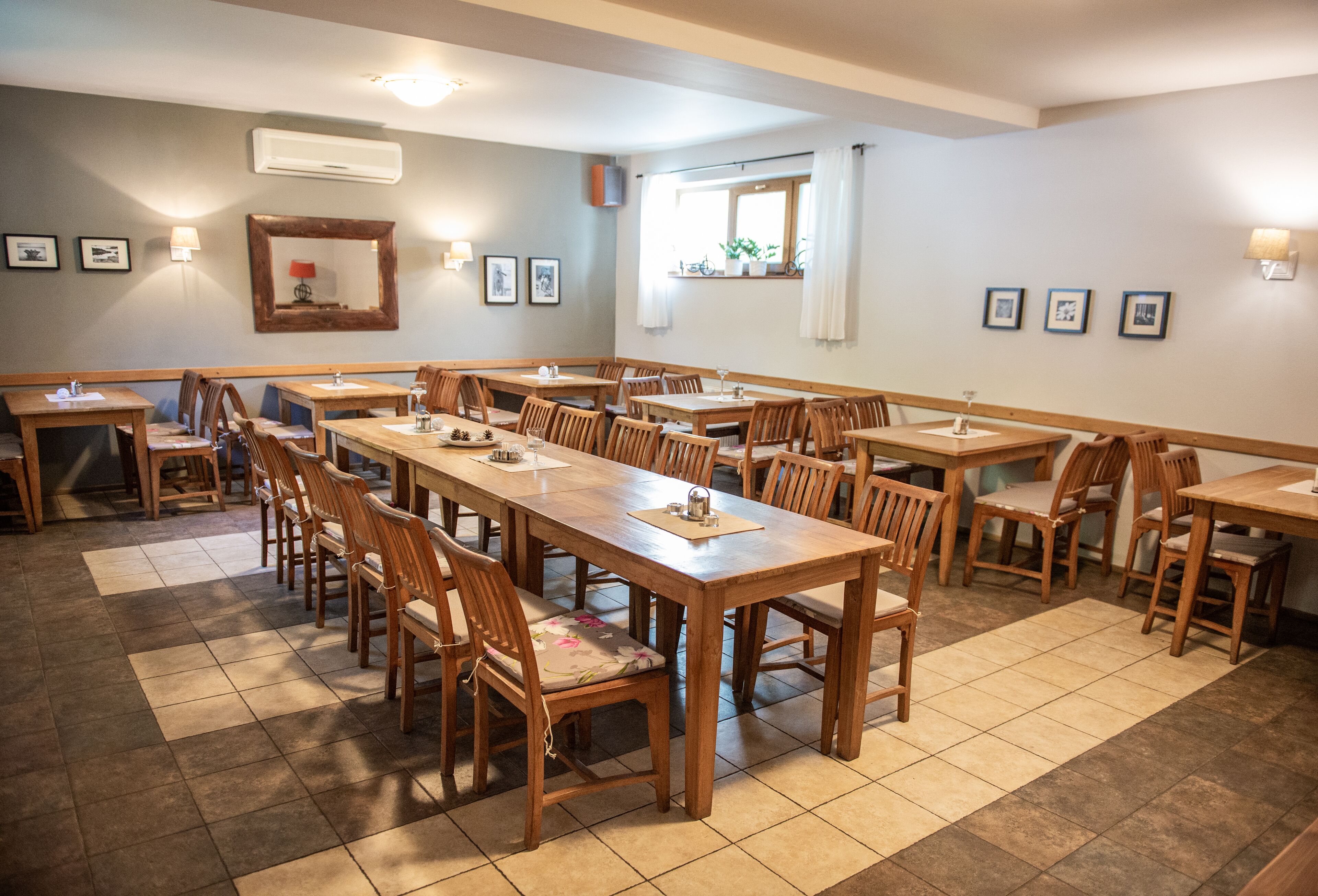 A dining area with multiple wooden tables and chairs, arranged in a spacious layout.