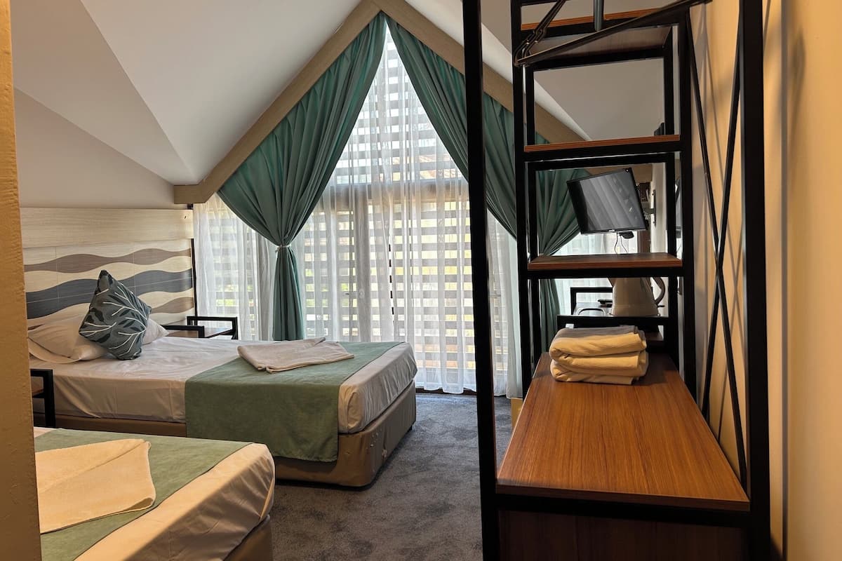 Una habitación con una cama litera, un escritorio, una silla y un televisor en un estante.