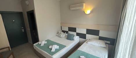 Quarto de hotel com duas camas, ar condicionado fixado na parede e uma porta.