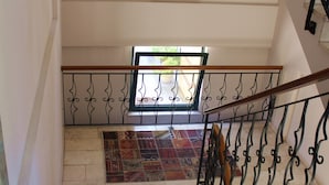 Una escalera con alfombra estampada, barandilla de metal y un cuadro en la pared.