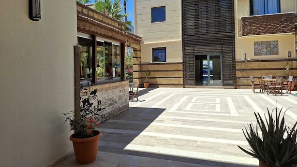 Un patio con suelo de baldosas, plantas en macetas y mobiliario exterior.