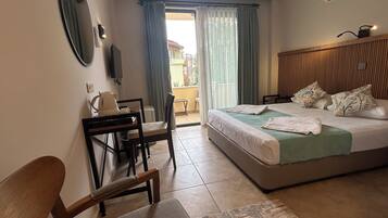 Una habitación de hotel con cama, escritorio, silla, televisor y ventana con cortinas.
