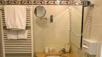 Un baño con lavamanos, espejo, toallero y retrete.