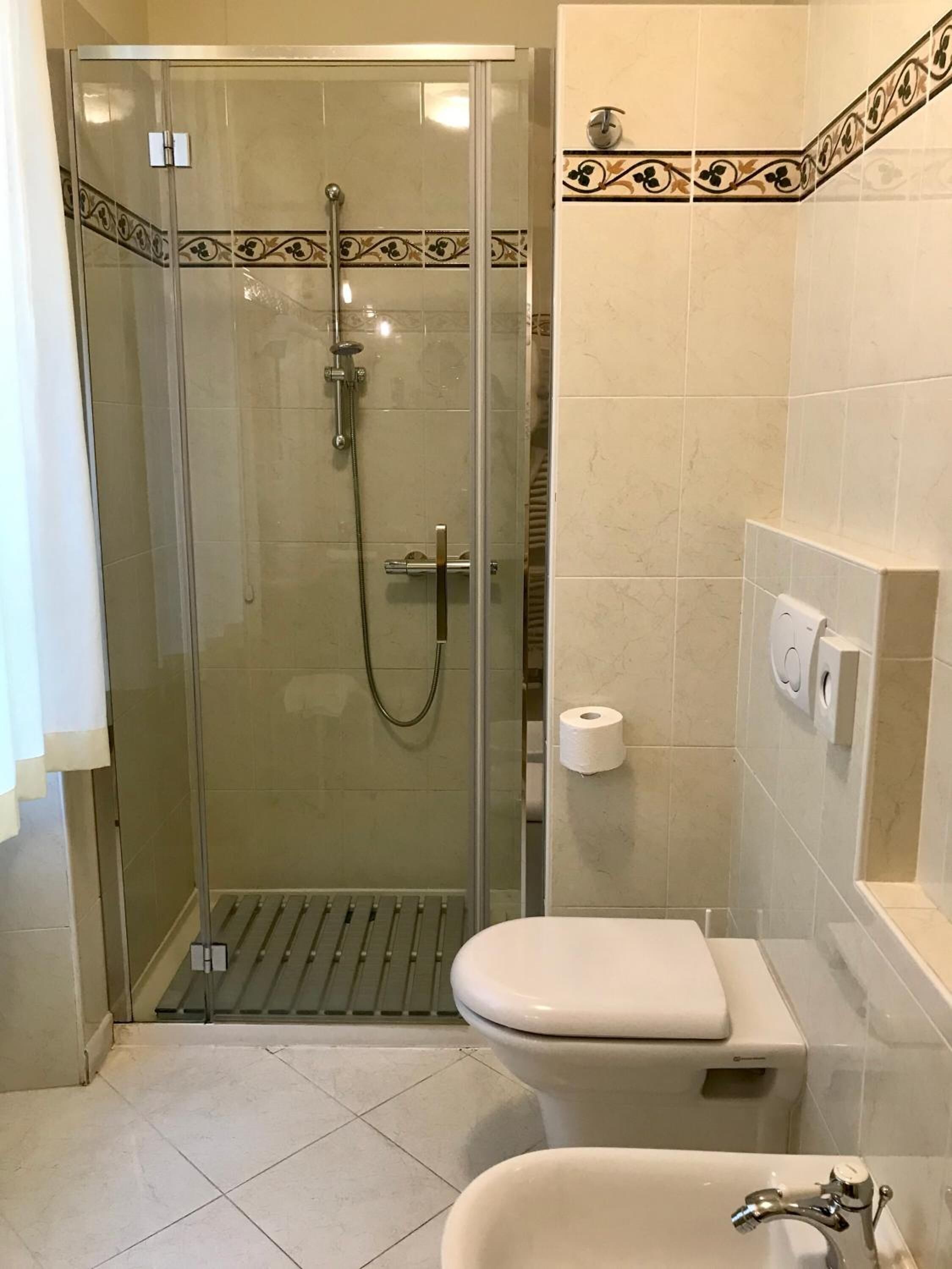 A bathroom with a glass-enclosed shower, a toilet, and a sink.