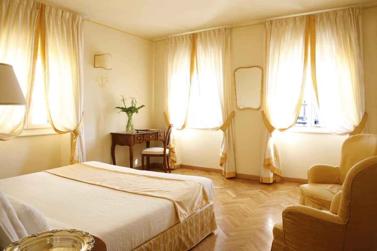 Une chambre d’hôtel avec un lit, un bureau, une chaise et un miroir.